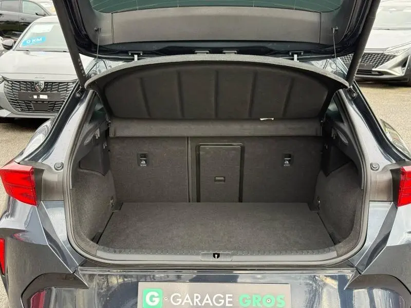 Coffre ouvert vu de l'arrière d'une CUPRA Formentor 1.5 eTSI Hybrid 2025 en gris magnétique mat, intérieur de coffre spacieux.