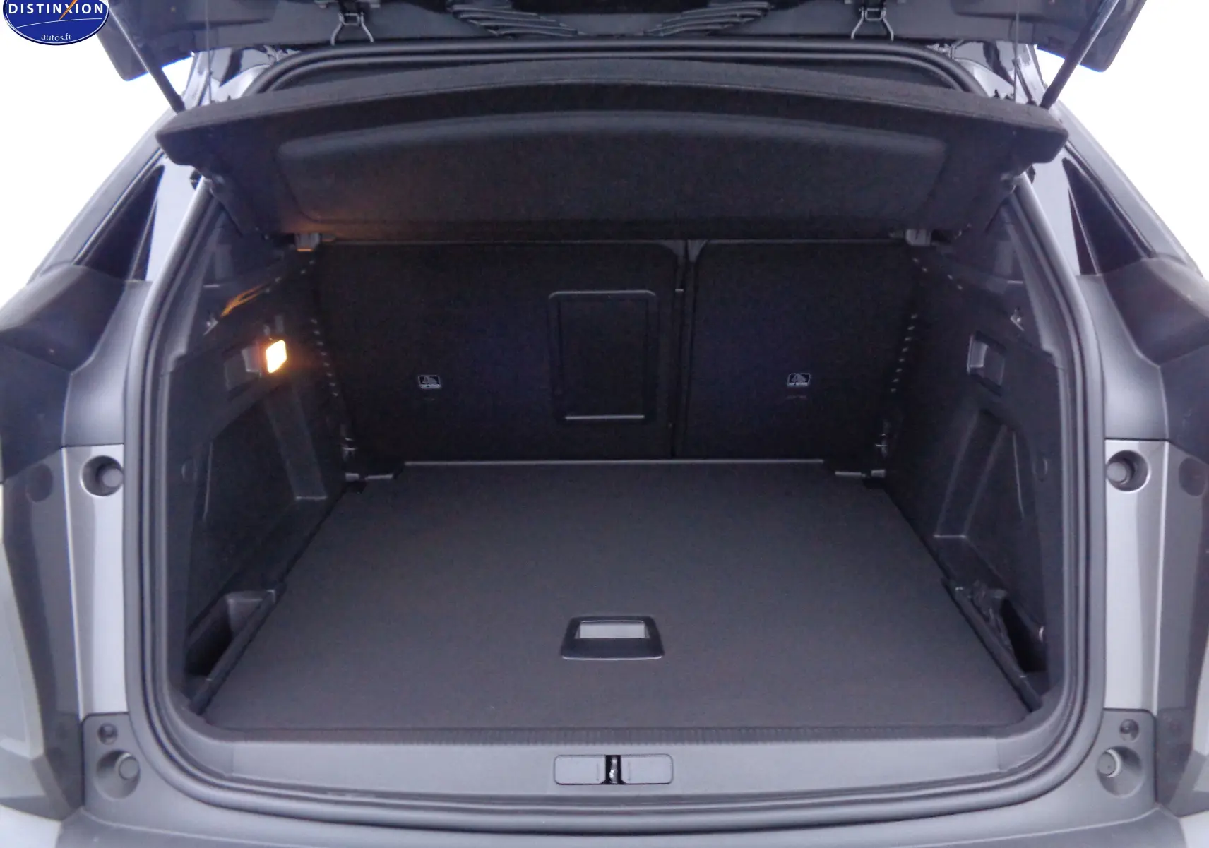 Coffre ouvert vu de l'arrière d'un Peugeot 3008 gris platinium métal, espace de chargement spacieux et bien éclairé.