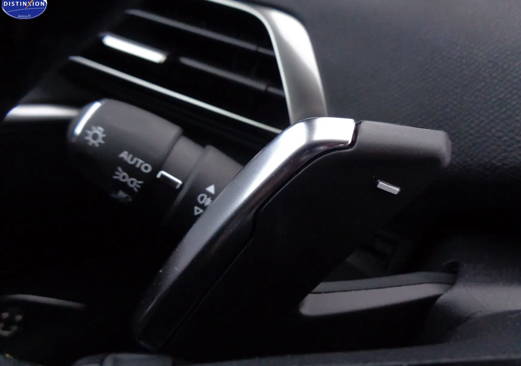 Gros plan sur la palette de changement de vitesse et la commande d'éclairage du Peugeot 3008 gris platinium métal 2023.