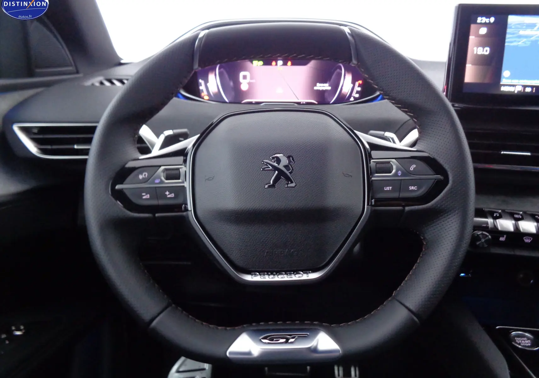 Gros plan sur le volant cuir perforé avec logo Peugeot et tableau de bord numérique du 3008 gris platinium 2023.