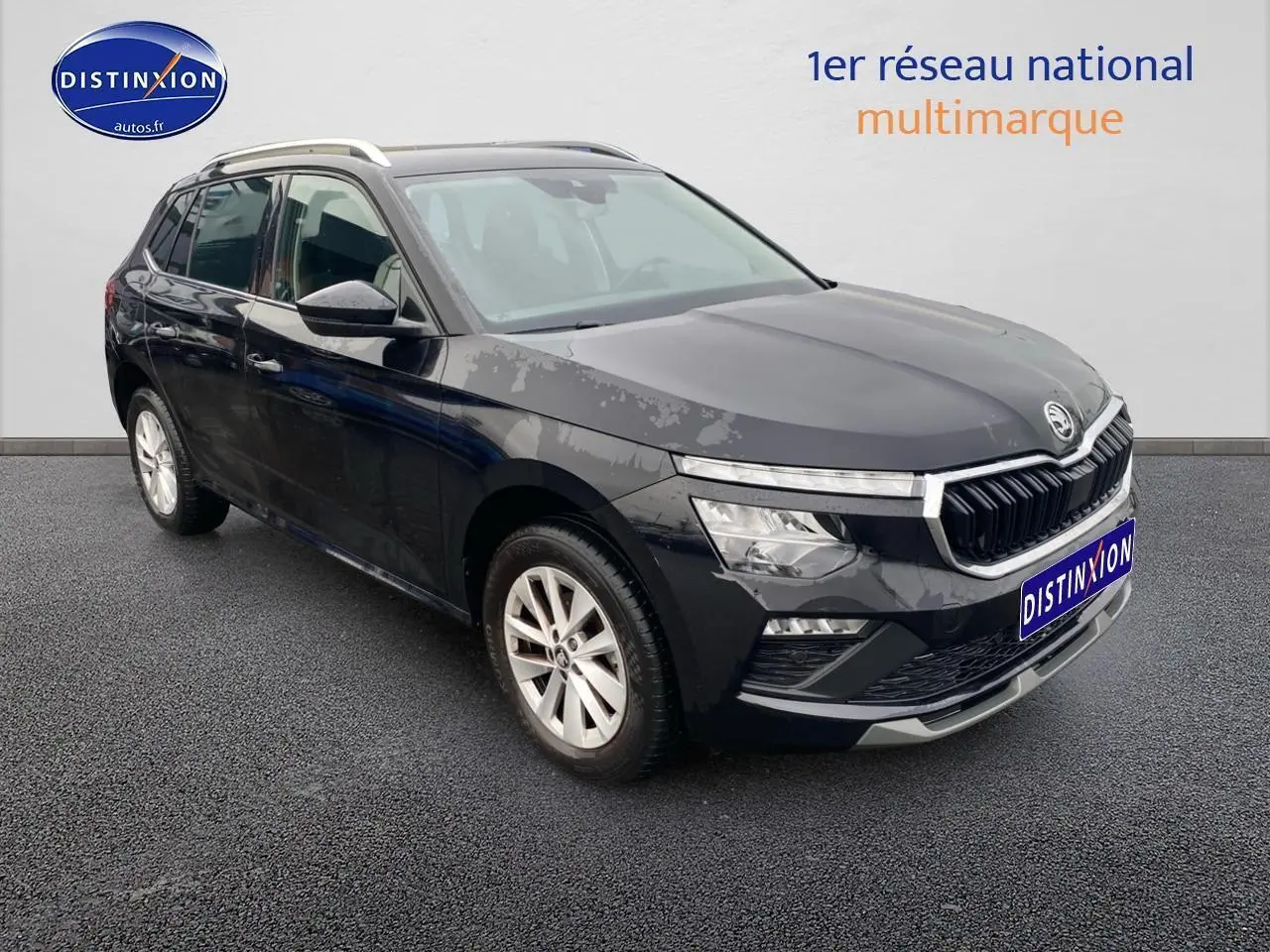 Vue 3/4 avant d'un Skoda Kamiq noir avec calandre chromée et jantes alu sur fond neutre.