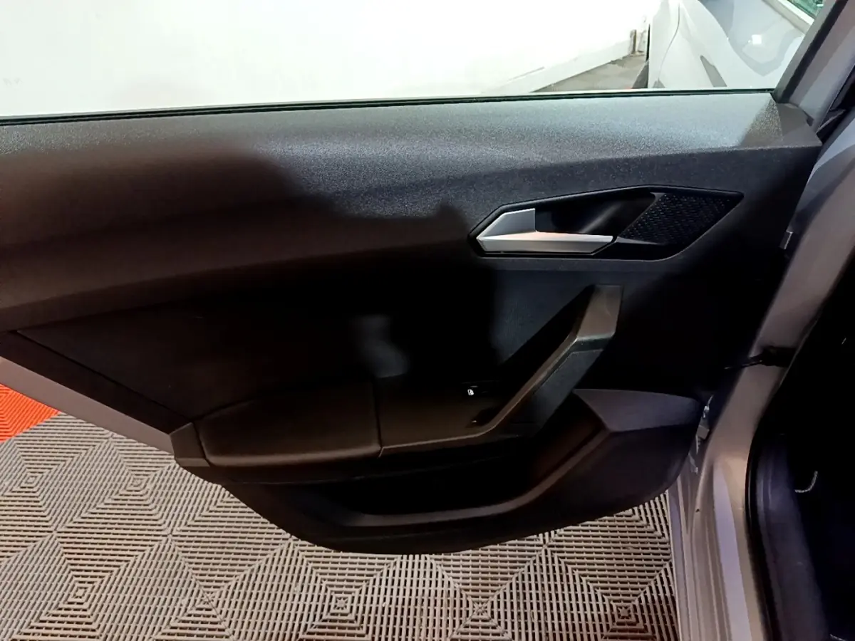 Vue intérieure de la porte avant droite d'une SEAT Leon gris foncé avec poignée argentée et panneau noir épuré.
