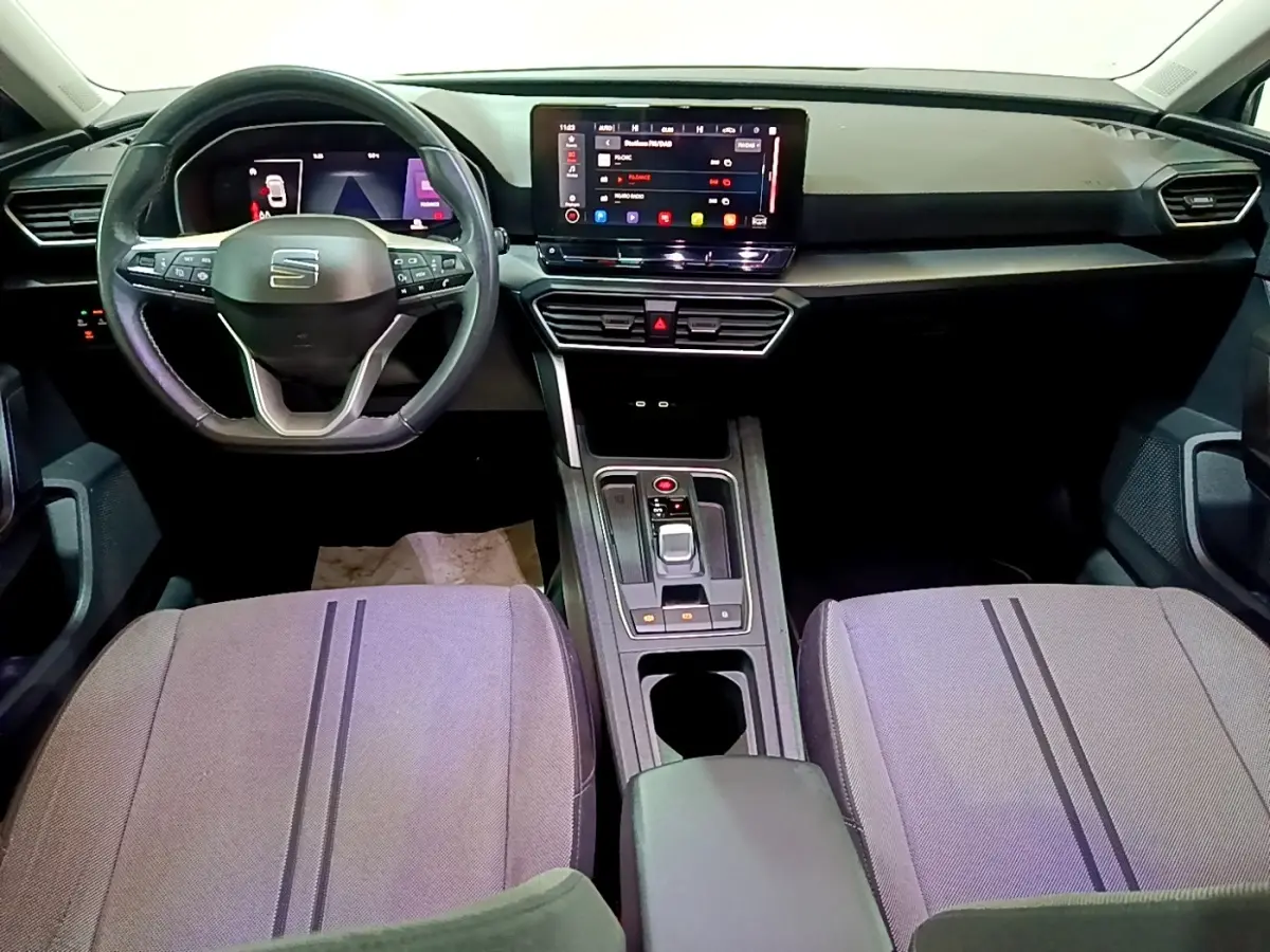 Vue intérieure avant du tableau de bord et volant cuir SEAT Leon gris foncé avec écran tactile central et commandes au volant.