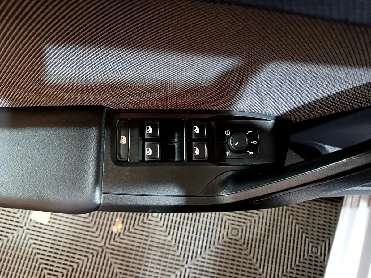 Vue rapprochée du panneau de commandes des vitres et rétroviseurs côté conducteur d’une SEAT Leon gris foncé.