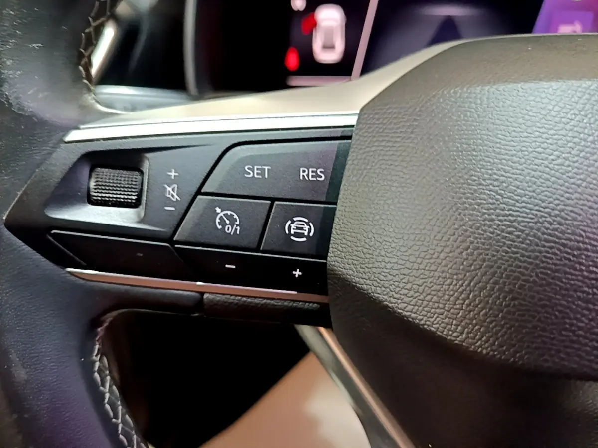 Gros plan sur les commandes de régulateur de vitesse au volant cuir noir du SEAT Leon gris foncé 2022.