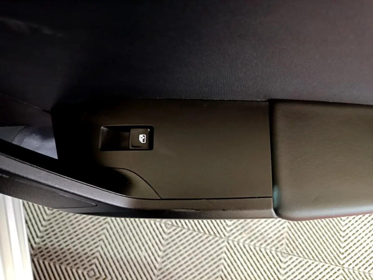 Détail du bouton d'ouverture de coffre sur l'accoudoir intérieur côté conducteur d'une SEAT Leon gris foncé.