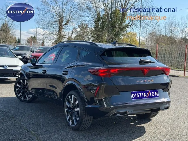 Vue 3/4 arrière droite d'un CUPRA Formentor 1.5 eTSI Hybrid noir minuit métallisé avec feux arrière reliés.