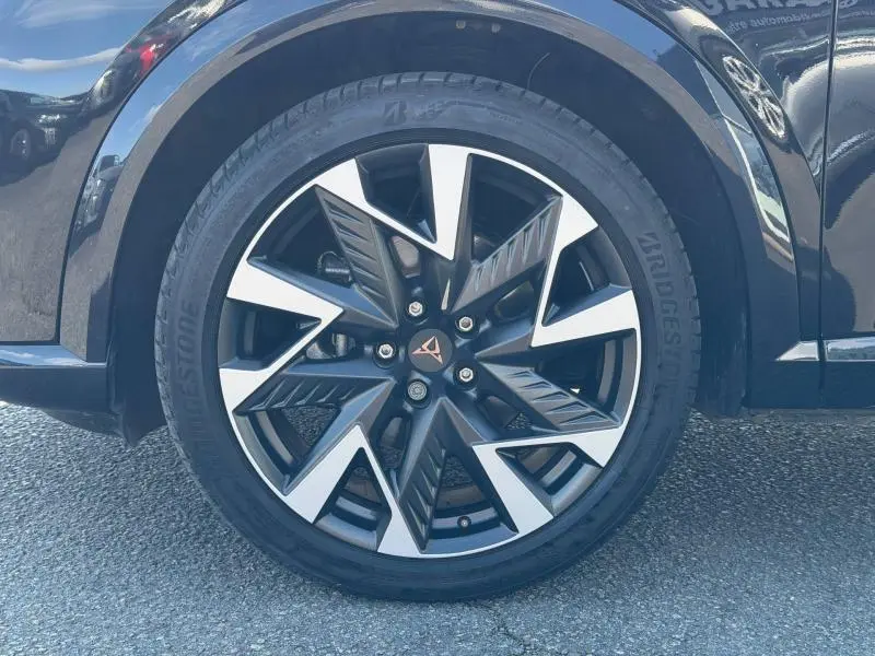 Gros plan sur la roue avant droite du CUPRA Formentor 1.5 eTSI Hybrid 2025 en Noir Minuit métallisé avec jante noire et argentée stylisée.