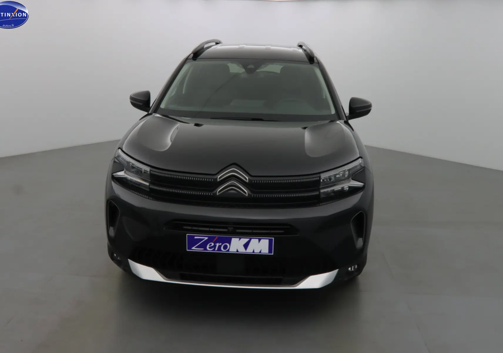 Vue frontale d'un Citroën C5 Aircross noir métal avec calandre distinctive et plaques "Zero KM" dans un studio.