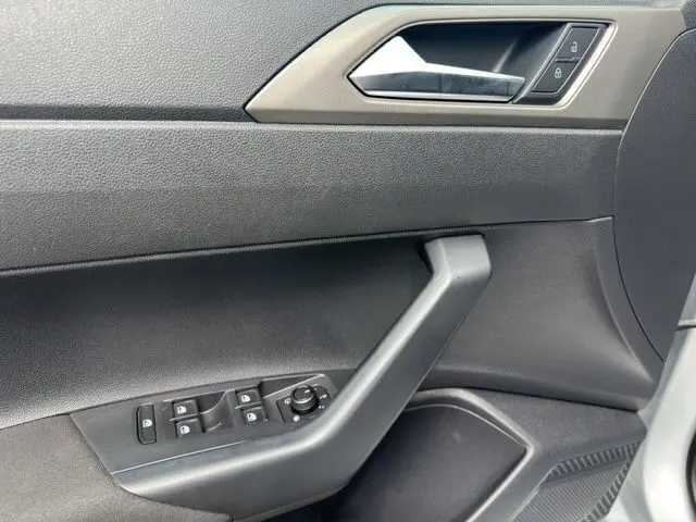 Gros plan sur la porte côté gauche d'une Volkswagen Polo gris 2021, avec commandes de vitres et poignée noire.