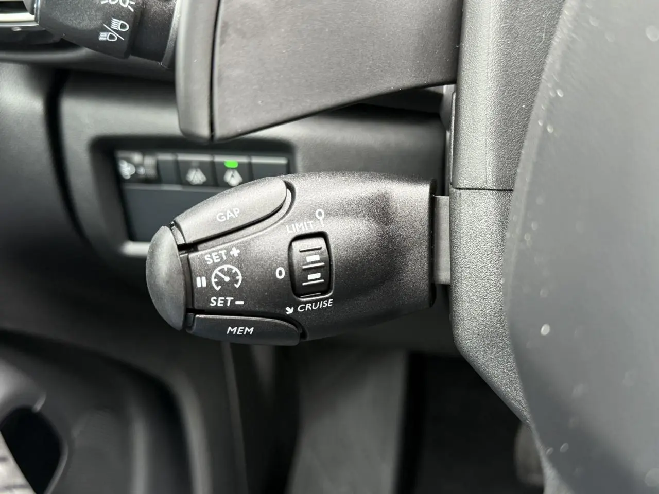 Gros plan sur la commande de régulateur de vitesse au volant d'un Citroën C5 Aircross Hybrid noir.