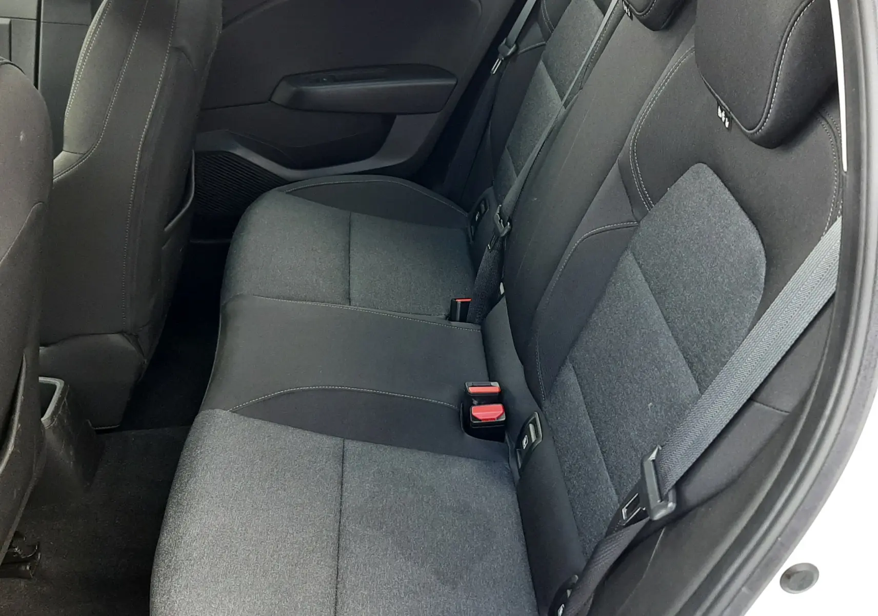 Vue intérieure côté droit des sièges arrière noirs en tissu de la Renault Clio V blanche, avec ceinture de sécurité visible.