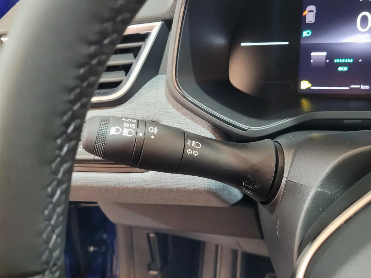 Gros plan sur la commande des phares et clignotants côté gauche du tableau de bord d’une Renault Clio bleu 2025.