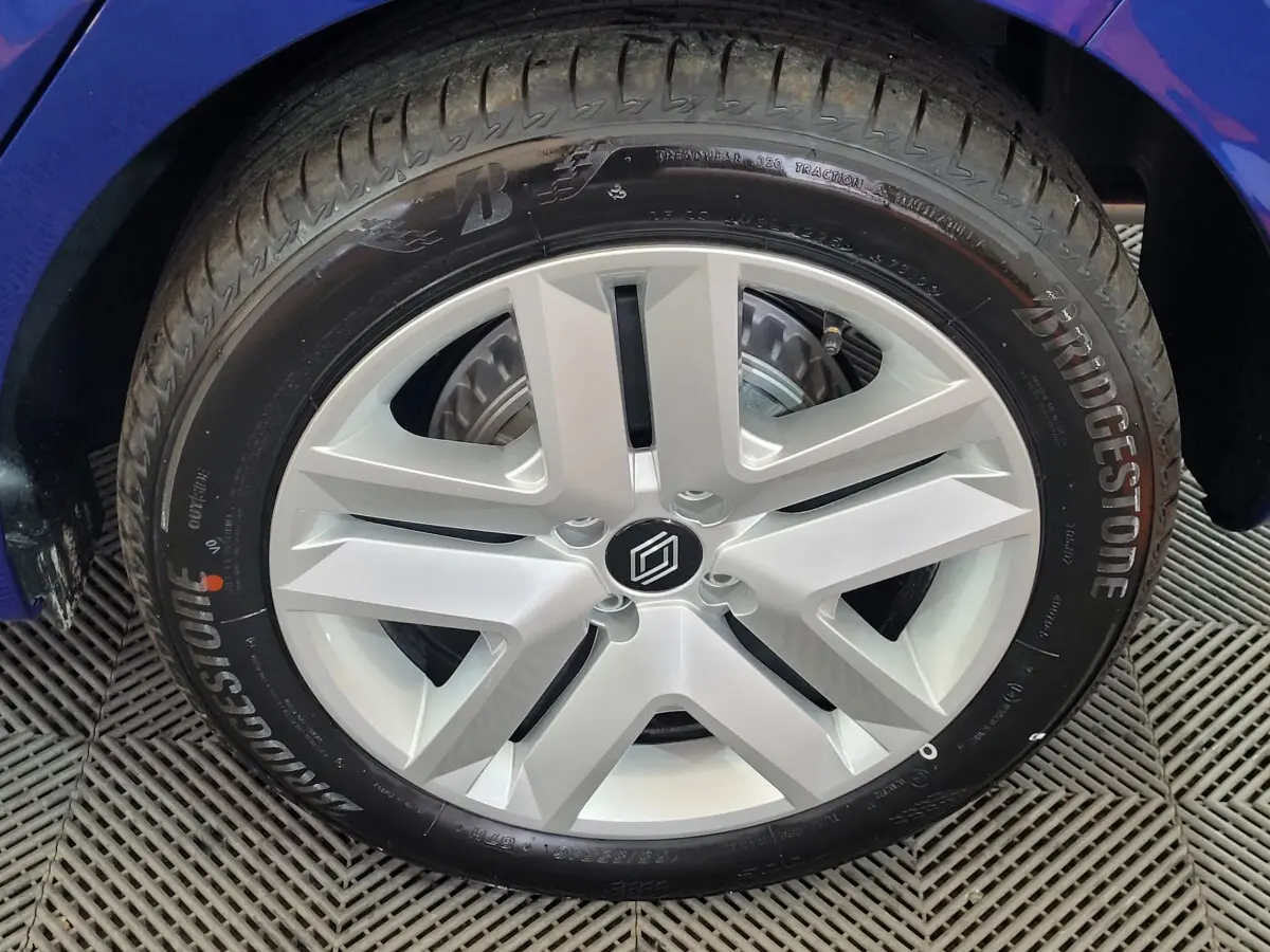 Gros plan sur la roue arrière droite d'une Renault Clio bleu, mettant en valeur le pneu Bridgestone et l'aile du véhicule.