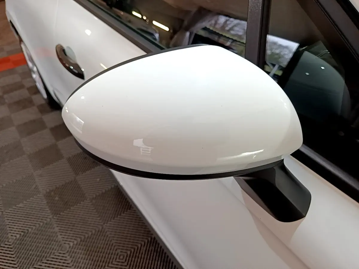 Gros plan sur le rétroviseur droit blanc de la Renault Clio Business 2021, avec porte et vitre partiellement visibles.