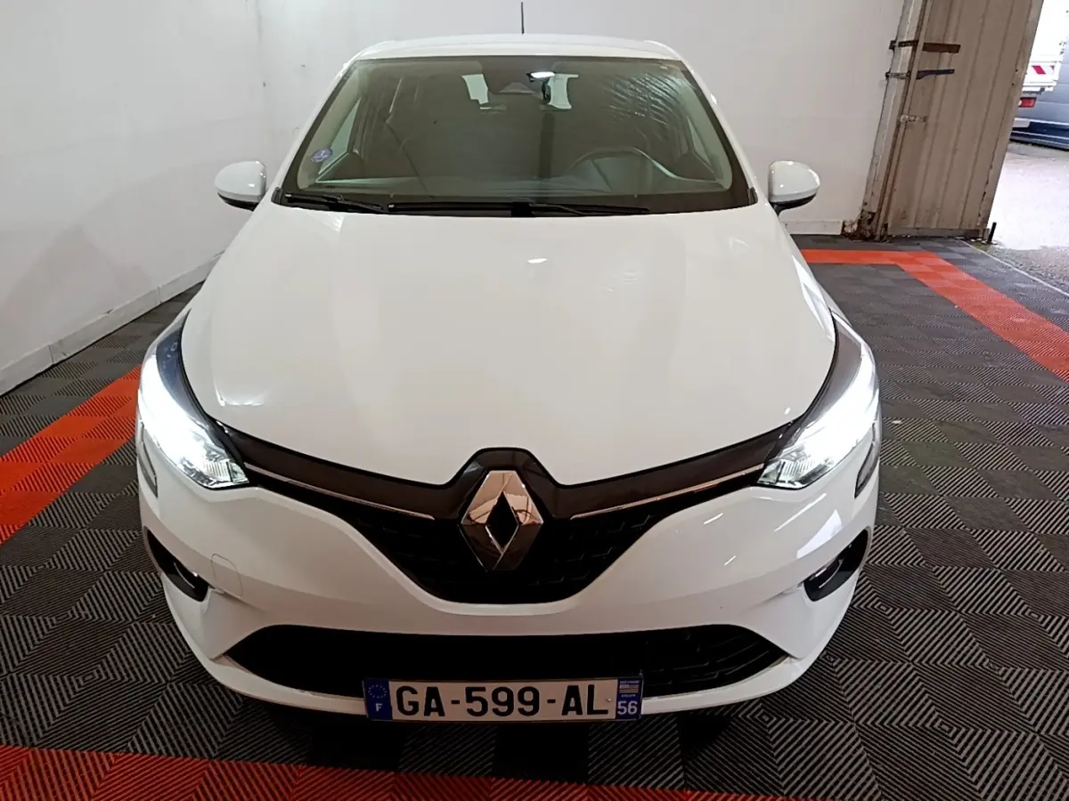 Vue frontale d'une Renault Clio Business blanche 2021 avec phares LED allumés dans un garage.