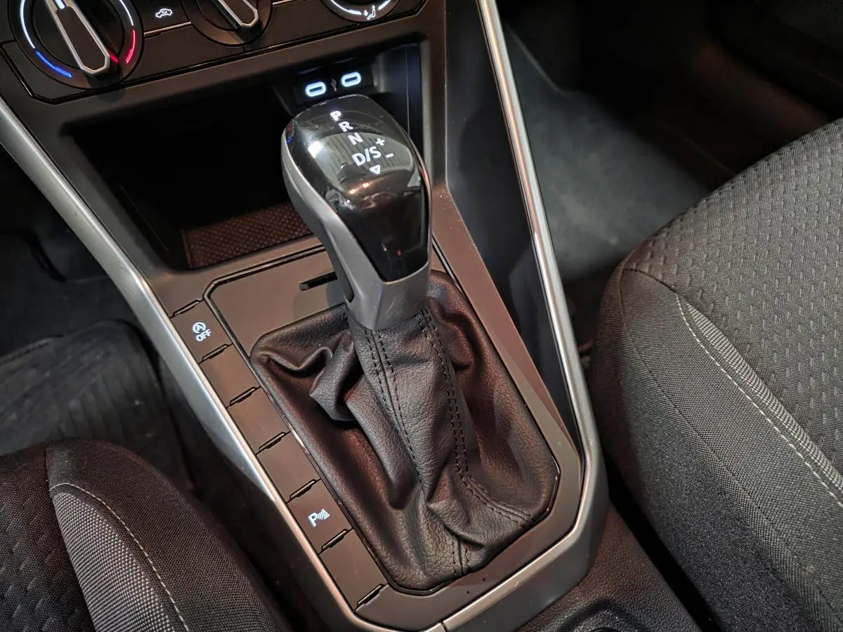 Le levier de vitesses automatique noir et argenté de la Volkswagen Polo 2025, avec sellerie tissu grise visible à droite.