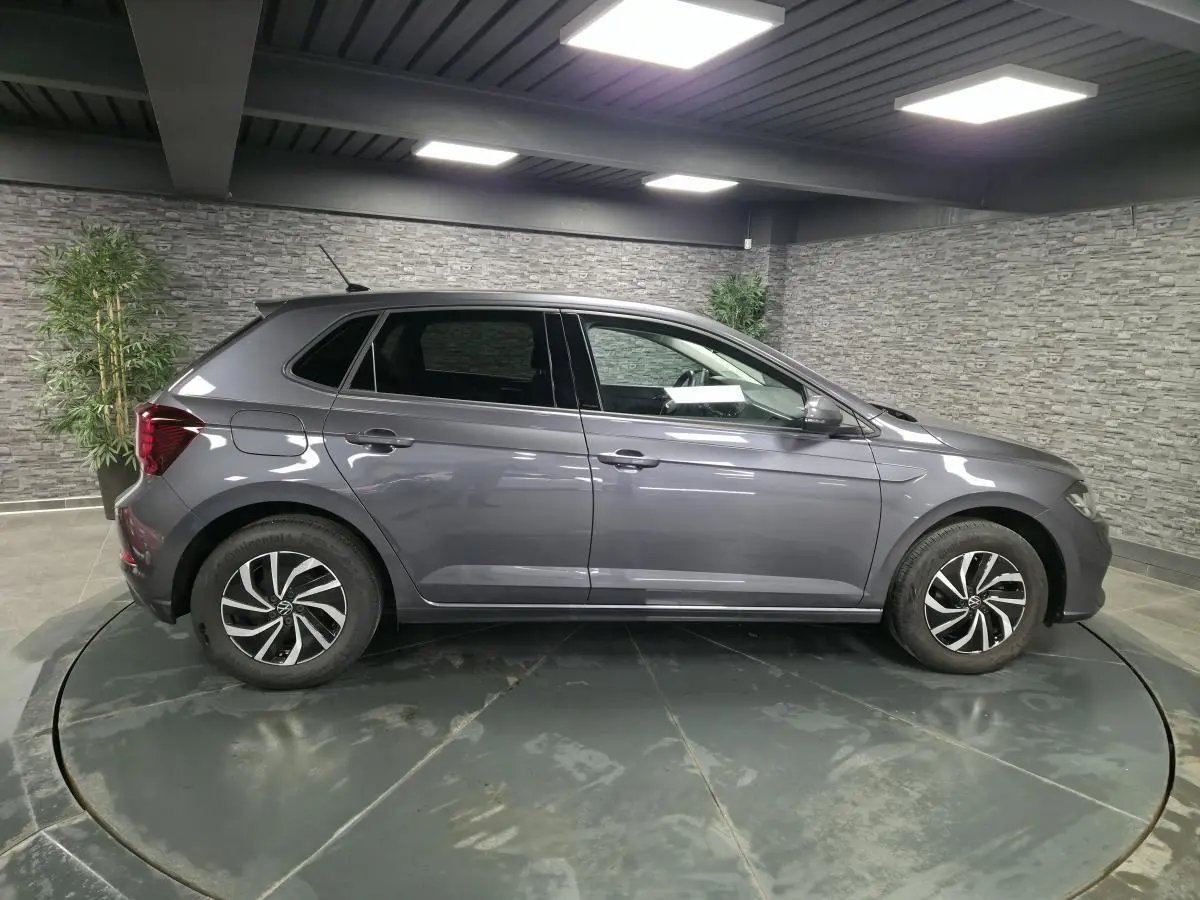 Volkswagen Polo gris métallisé vue de profil côté gauche avec jantes alliage et antenne de toit.