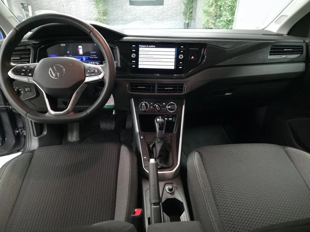 Vue intérieure avant de la Volkswagen Polo 2025 gris, tableau de bord avec écran tactile et volant cuir multifonction.
