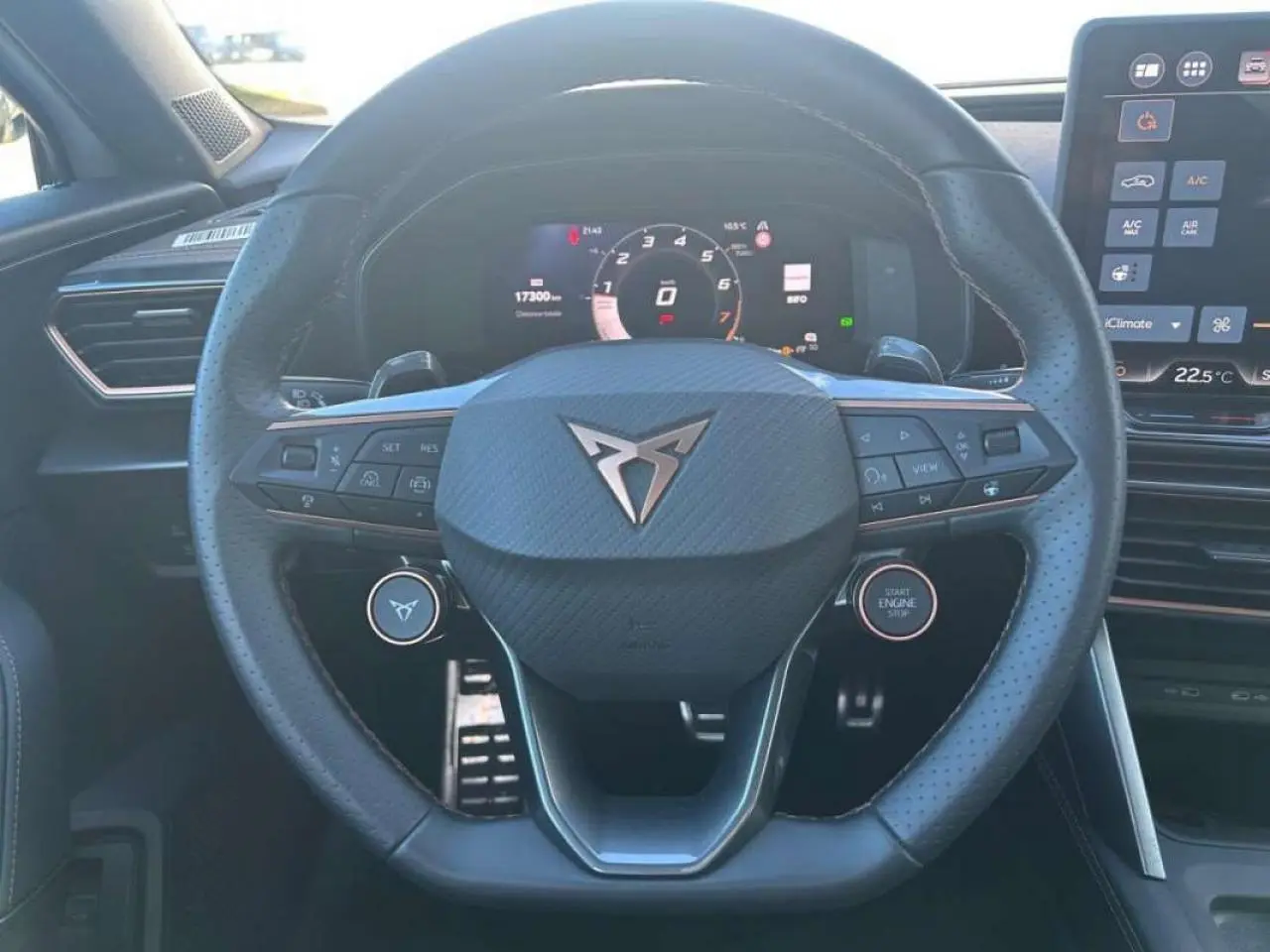 Vue rapprochée du volant noir perforé avec logo CUPRA au centre, tableau de bord numérique et écran tactile à droite.