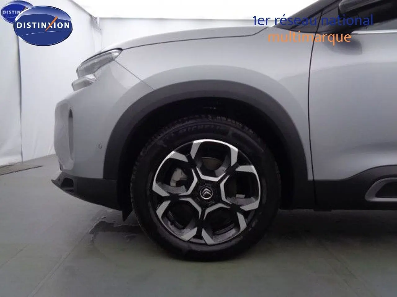 Gros plan sur la roue avant gauche du Citroën C5 Aircross gris Artense avec jante alliage bicolore au design moderne.