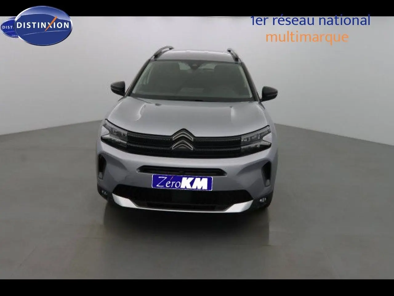 Vue frontale d'un Citroën C5 Aircross gris Artense métal avec calandre noire et plaques d'immatriculation bleues Zero KM.