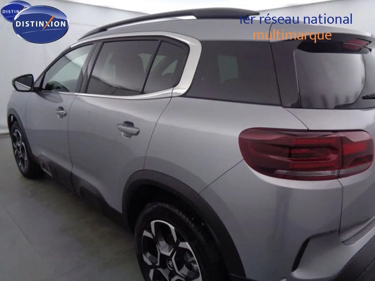 Vue 3/4 arrière gauche d'un Citroën C5 Aircross gris Artense métal avec toit noir et jantes bicolores.