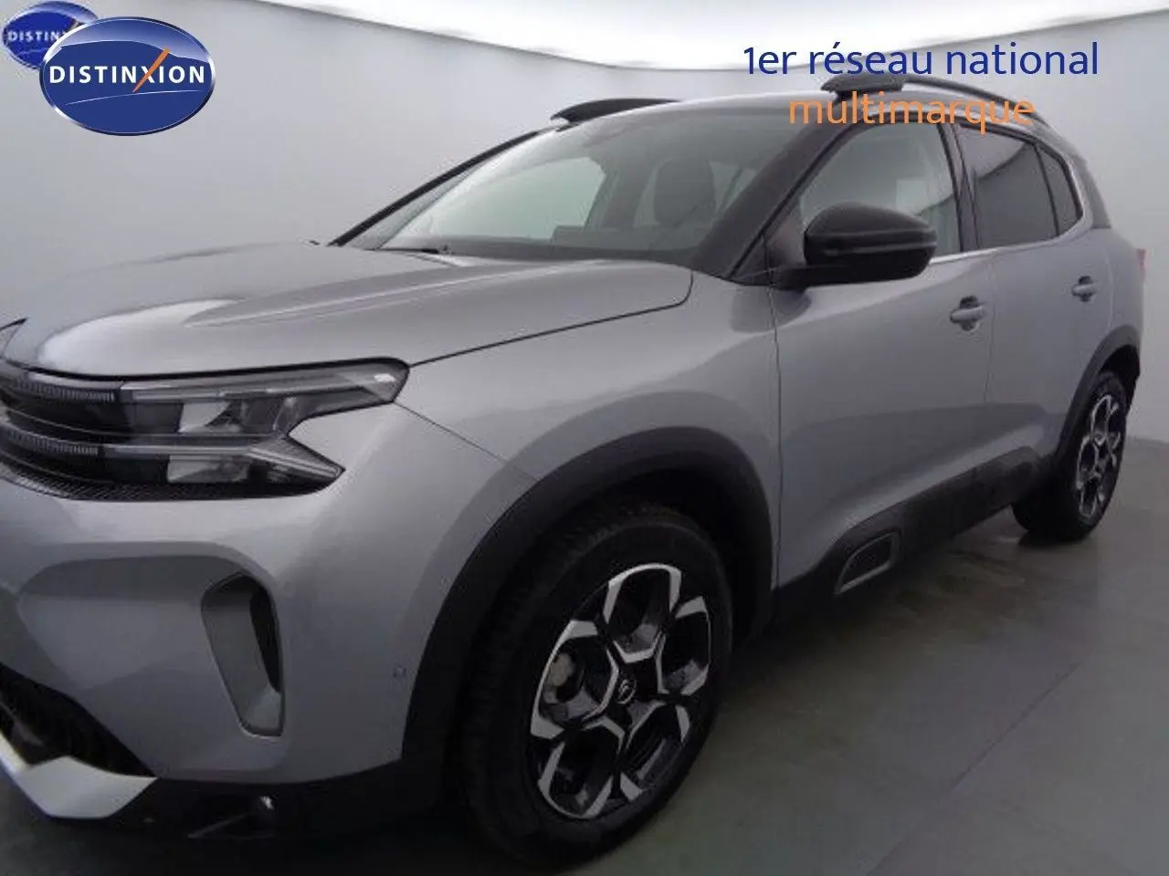 Vue 3/4 avant droit d'un Citroën C5 Aircross gris Artense métallisé avec jantes bi-ton et toit noir contrasté.