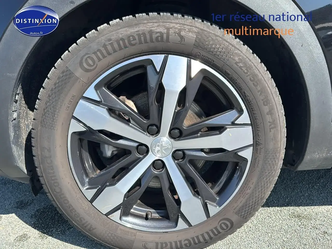 Gros plan sur la jante alu bi-ton noire et argent avec logo Peugeot sur un Peugeot 3008 noir métal.