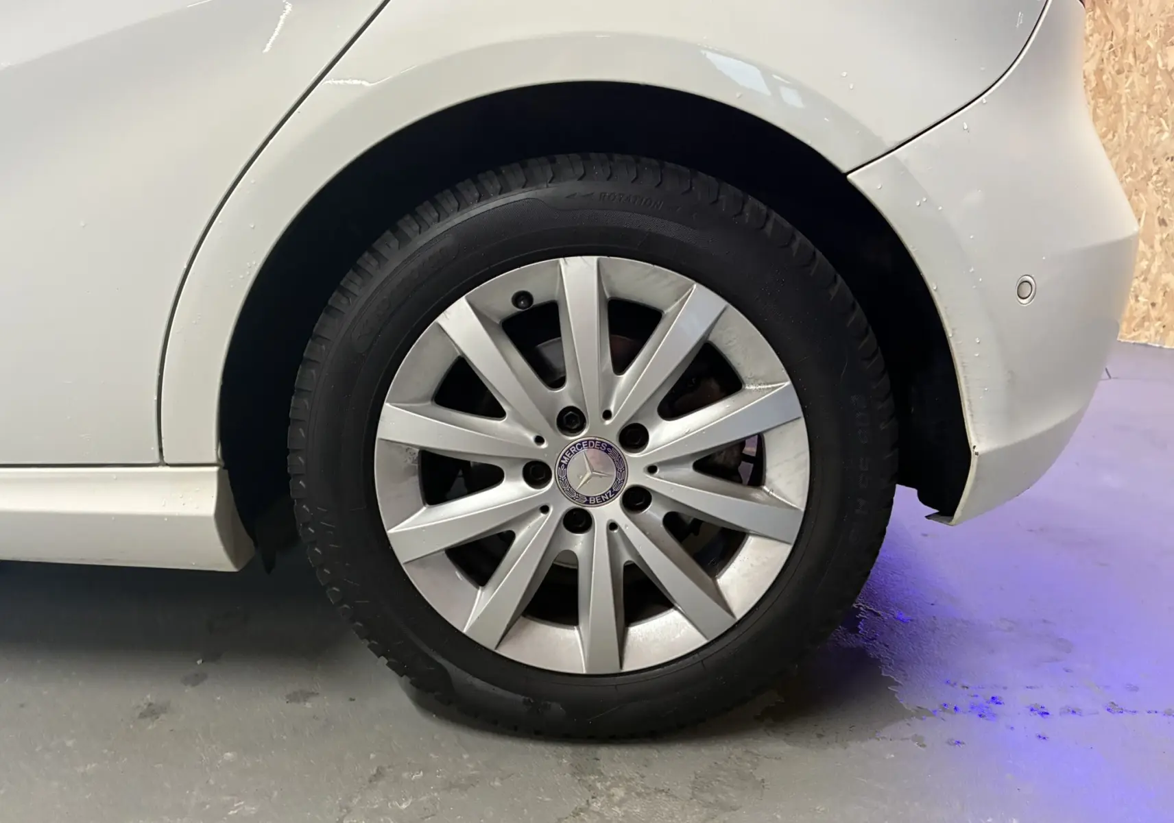 Gros plan sur la roue arrière droite blanche d'une Mercedes Classe A 200D 2016 avec jante argentée et logo Mercedes visible.