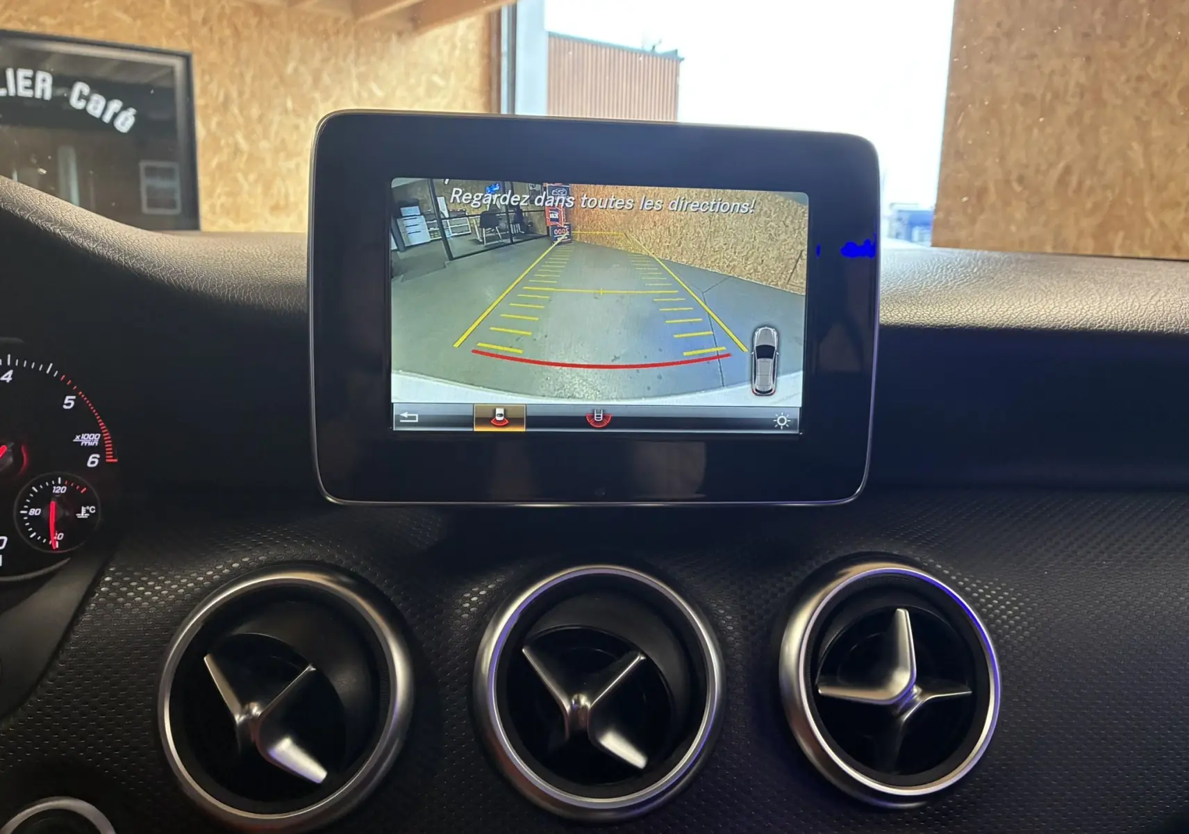 Écran central de la Mercedes Classe A 200D 2016 affichant la caméra de recul, avec les aérateurs ronds en aluminium brossé.