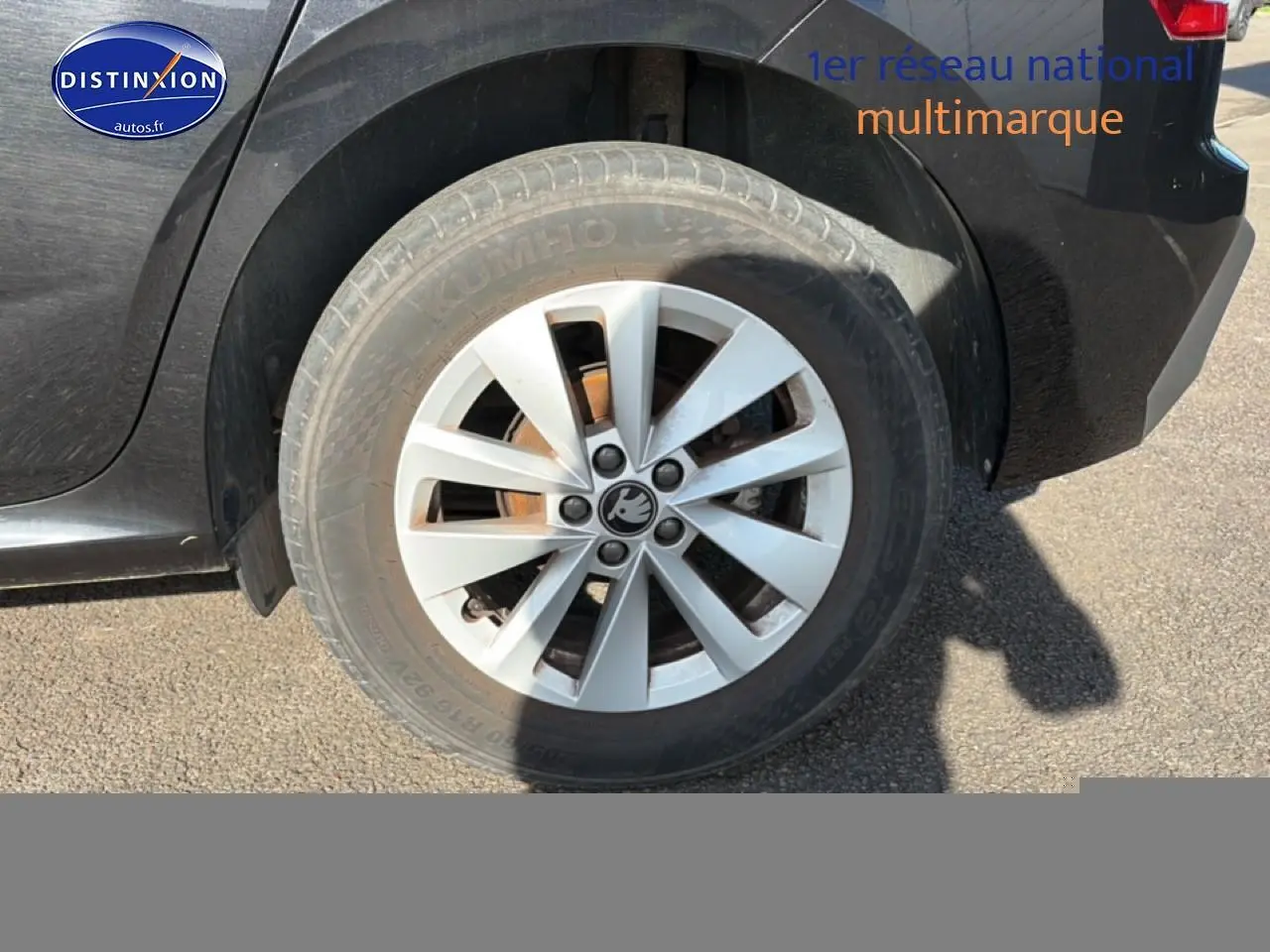 Gros plan sur la roue arrière droite d'une Skoda Kamiq noire avec jante alu et logo Skoda visible.