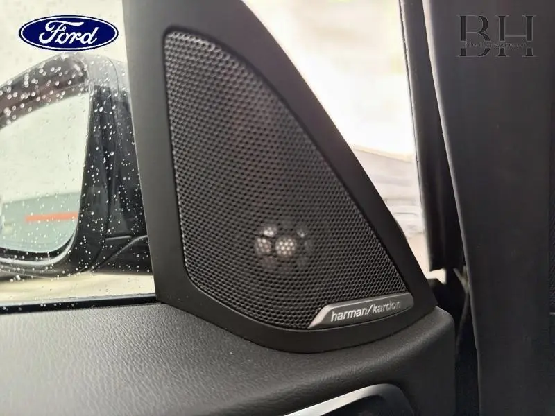 Gros plan sur le haut-parleur Harman Kardon noir côté gauche dans l'habitacle d'une BMW Série 4 Gran Coupé Saphirschwarz.