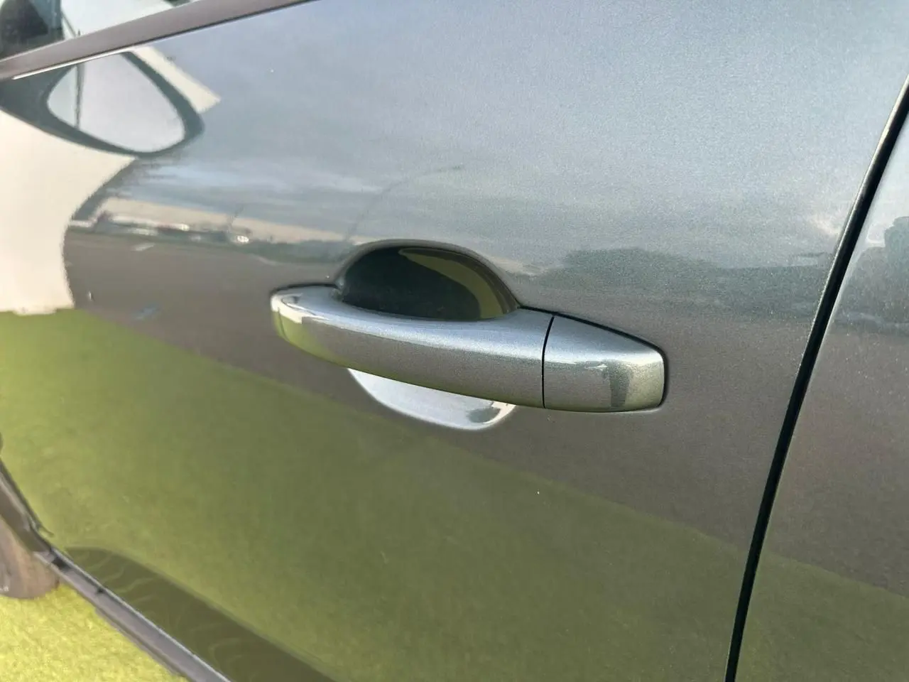 Poignée de porte côté gauche en gros plan sur une Dacia Sandero III Stepway vert cèdre.