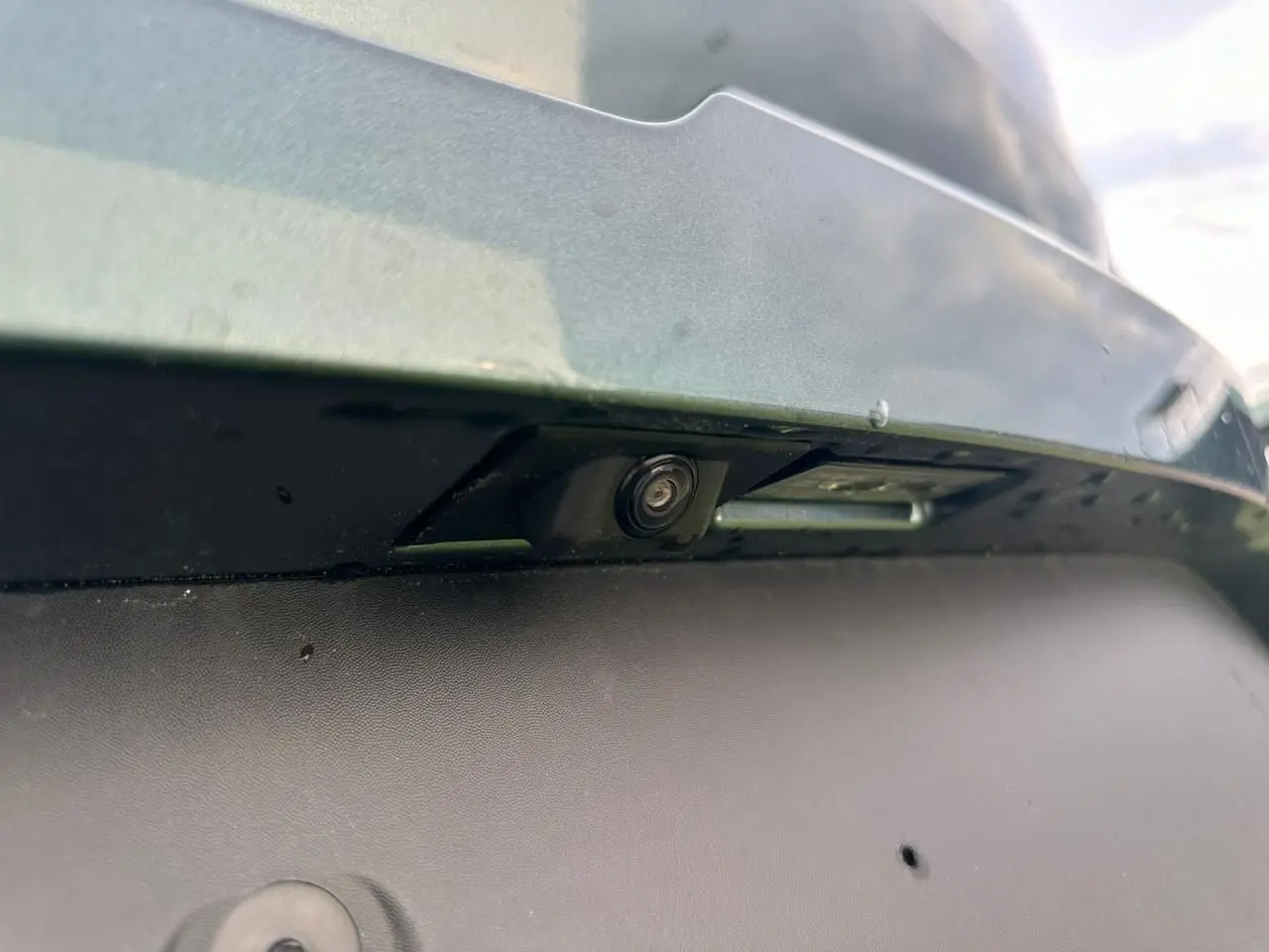 Gros plan sur la caméra de recul intégrée au pare-chocs arrière du Dacia Sandero III Stepway vert cèdre.
