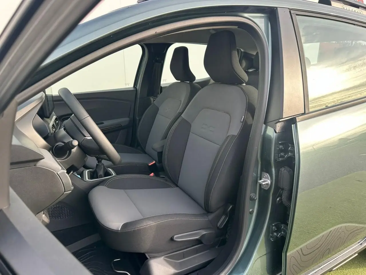 Vue intérieure côté conducteur de la Dacia Sandero III Stepway vert cèdre, montrant les sièges avant et le volant.