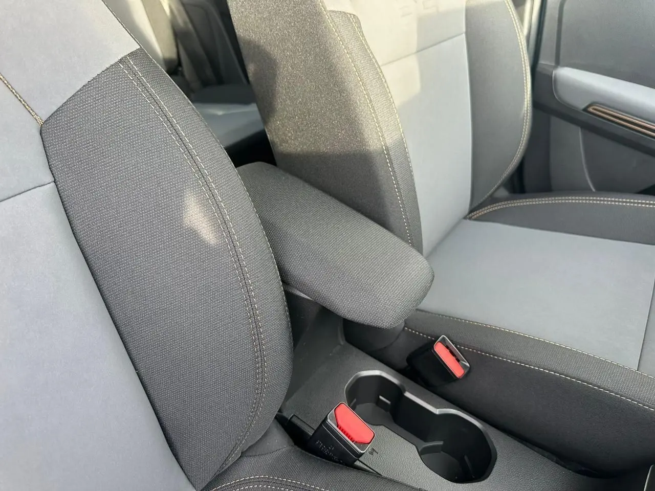 Gros plan sur l'accoudoir central et les sièges avant gris foncé avec surpiqûres contrastantes du Dacia Sandero Stepway 2025.