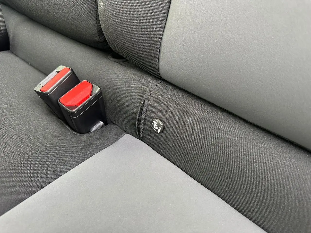 Détail de la banquette arrière noire avec ceintures rouges et logo Isofix sur la DACIA Sandero III Stepway.