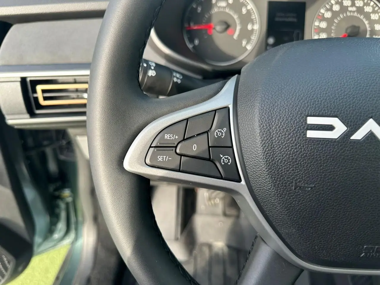 Gros plan sur le volant noir de la Dacia Sandero III Stepway avec commandes de régulateur de vitesse visibles.
