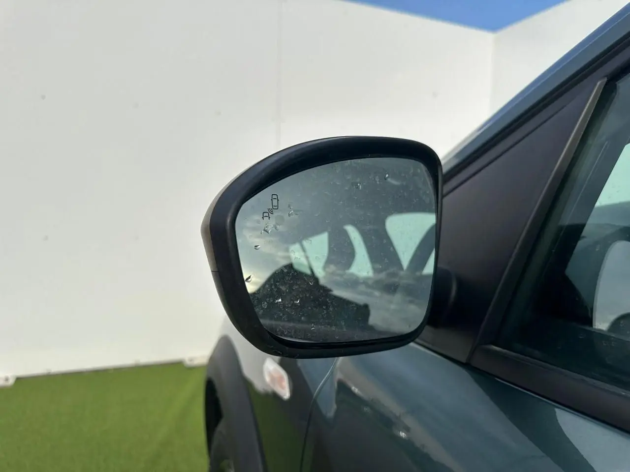Rétroviseur droit de la Dacia Sandero III Stepway vert cèdre, avec détecteur d'angle mort visible.