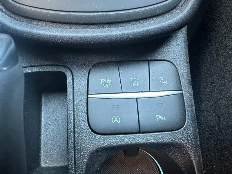 Gros plan sur les commandes de la console centrale du Ford Puma 2024 gris Solar Métallisé, avec boutons d'assistance et arrêt auto.