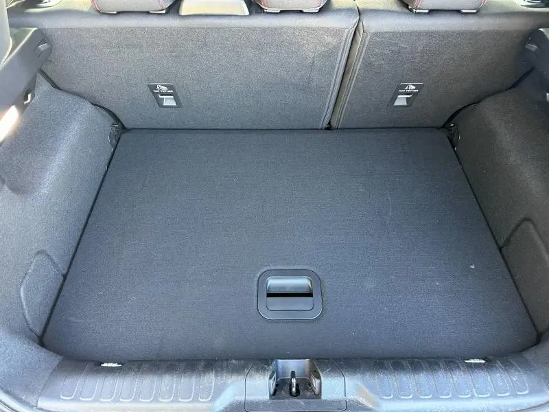 Vue plongeante sur le coffre spacieux et tapissé en tissu noir du Ford Puma 2024 Gris Solar Métallisée.