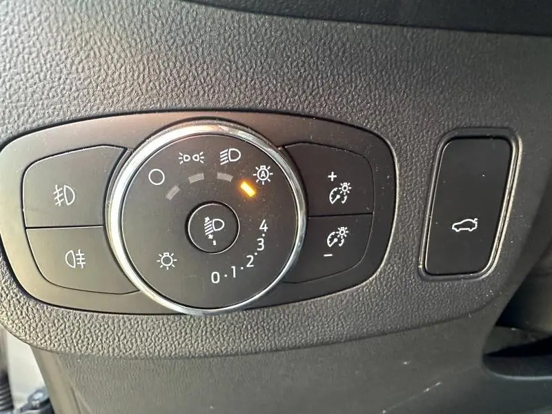 Gros plan sur le bouton de réglage des phares et commandes d’éclairage du Ford Puma 2024 en gris Solar Métallisée.