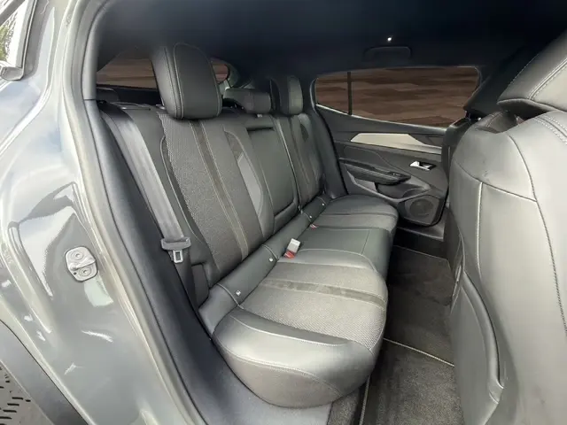 Vue intérieure arrière côté gauche du Peugeot 408 Hybrid 145 e-DCS6 GT gris clair, sièges en cuir et tissu, banquette 3 places.