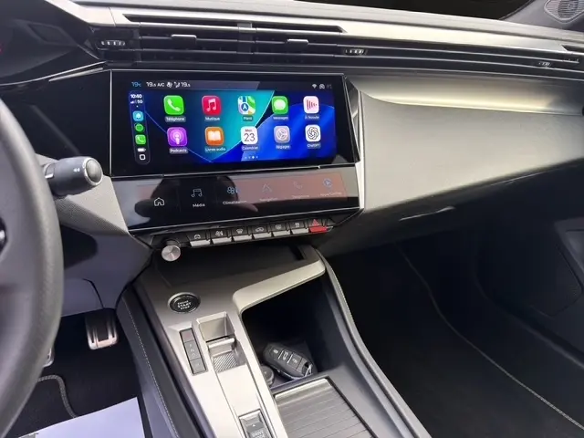 Vue intérieure du tableau de bord et console centrale du Peugeot 408 Hybrid gris clair, avec écran tactile multifonctions allumé.