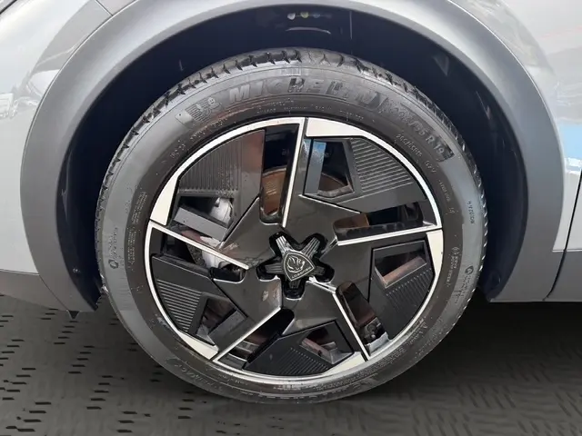 Gros plan sur la roue avant droite d'une Peugeot 408 Hybrid 145 e-DCS6 GT gris clair avec jante noire et argentée.