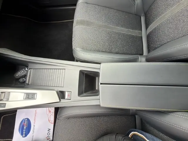 Vue intérieure rapprochée du tunnel central et des sièges en tissu gris foncé de la Peugeot 408 Hybrid 145 e-DCS6 GT.
