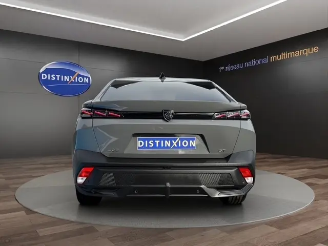 Vue arrière d'une Peugeot 408 Hybrid 145 GT gris clair dans un showroom avec feux LED et logo distinctif au centre.