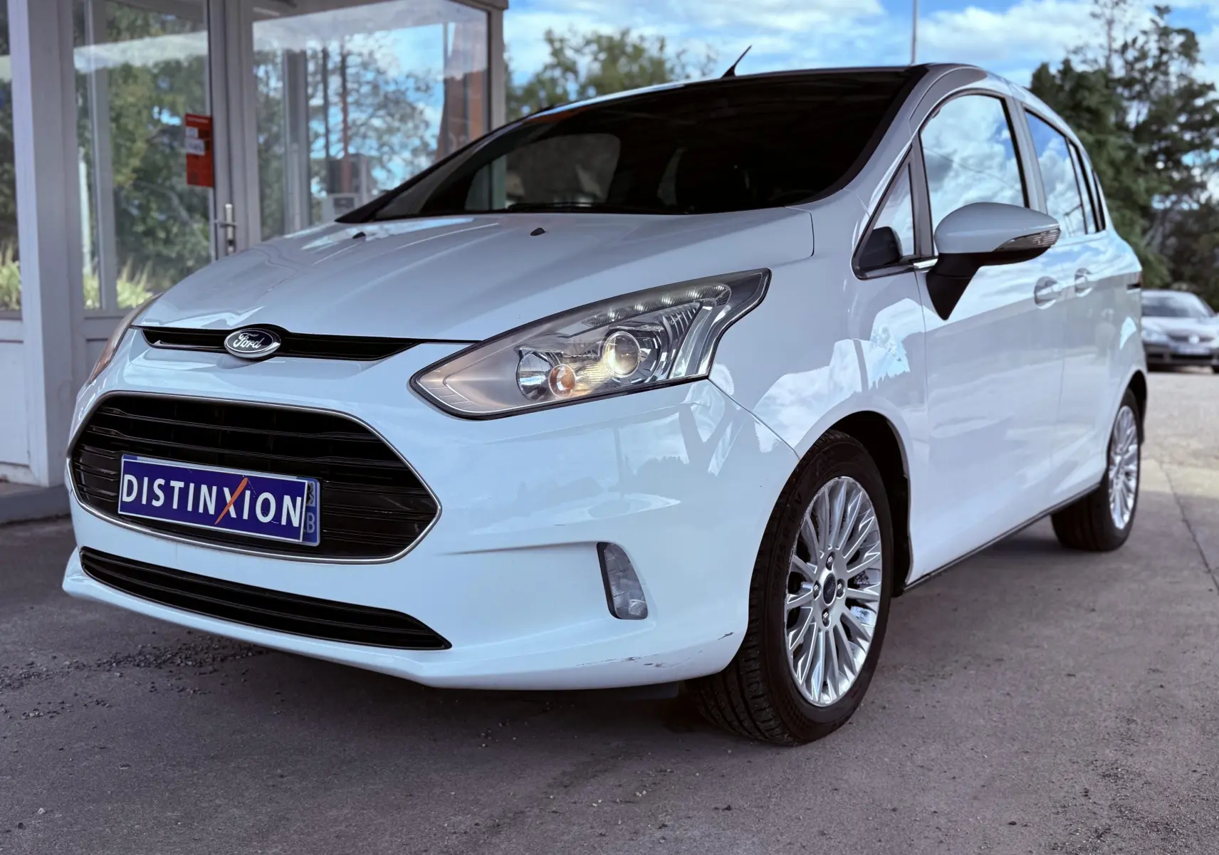 Ford B-MAX blanc en vue 3/4 avant droit, avec calandre noire et jantes alliage visibles.