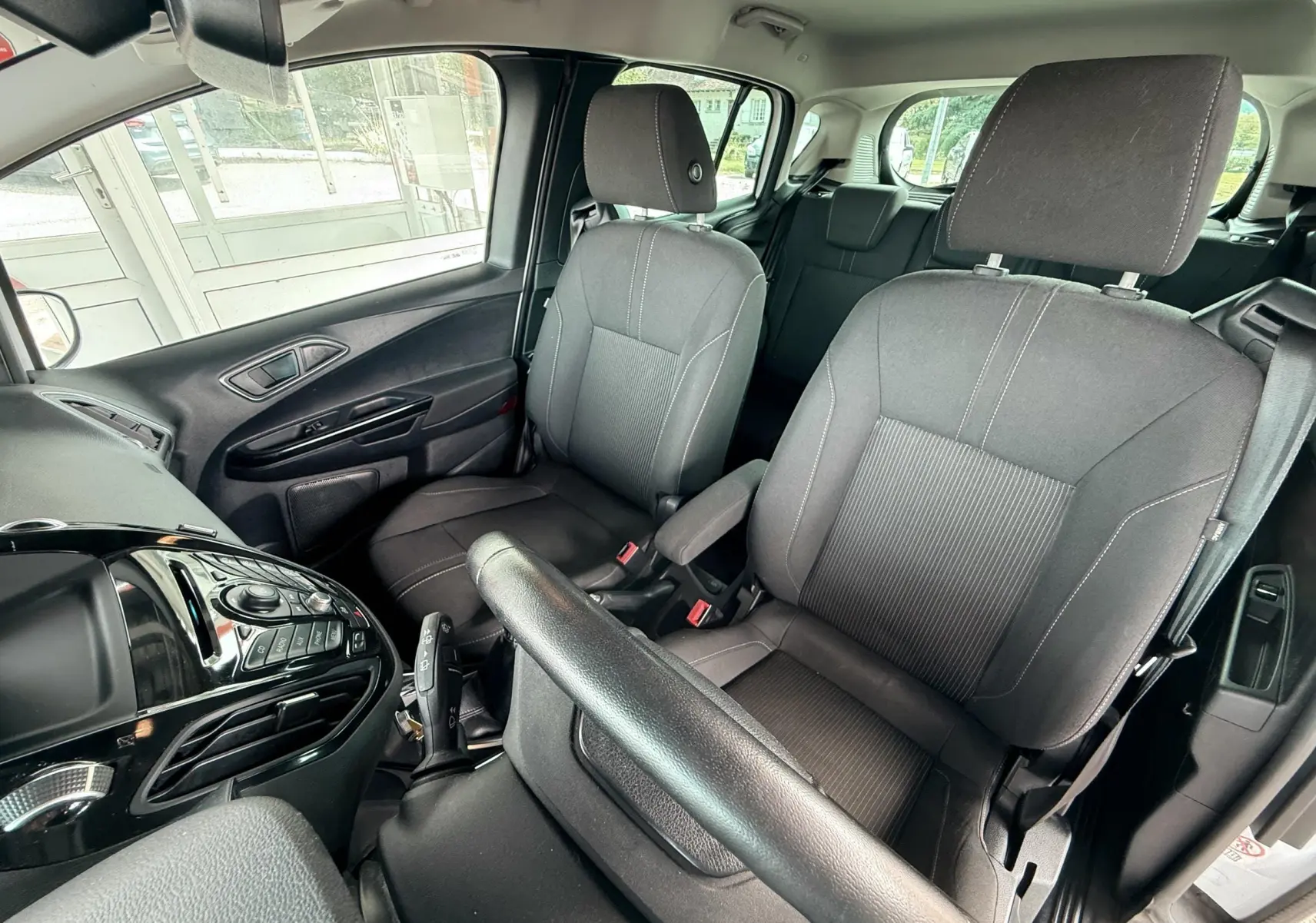 Intérieur avant du Ford B-MAX 2014 montrant les sièges en tissu gris et la console centrale noire brillante.
